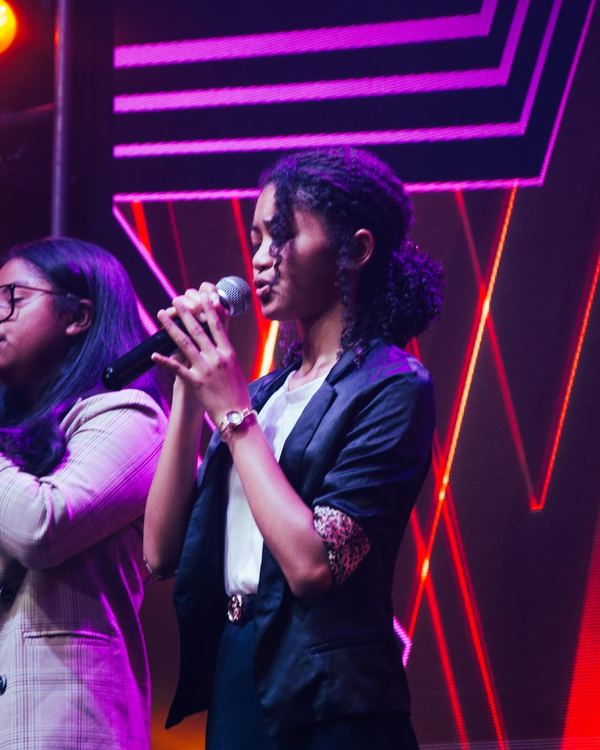 Chanteuse au micro devant les néons du plateau
